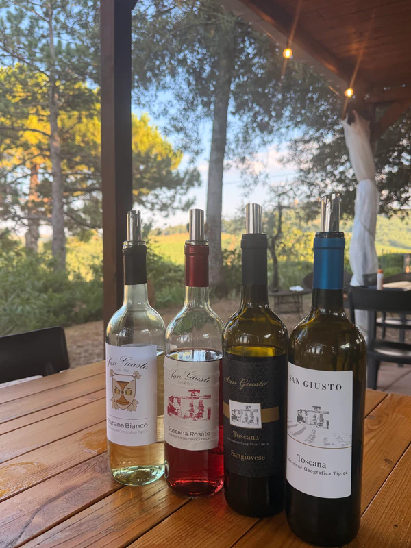 I quattro vini San Giusto sul tavolo della degustazione, con le colline sullo sfondo