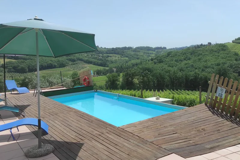 Terrazza in legno con ombrellone accanto alla piscina